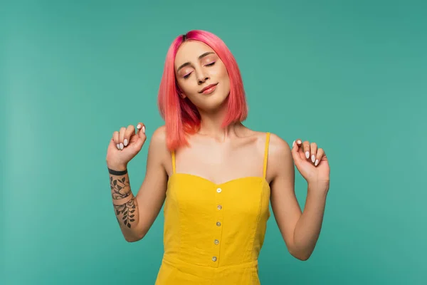 Tattooed young woman with pink dyed hair and closed eyes isolated on turquoise — Stock Photo