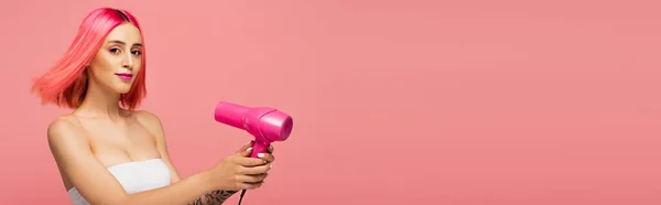 Молодая женщина с красочными волосами проведение фен изолированы на розовый, баннер — стоковое фото