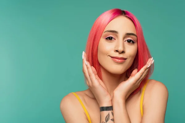 Tattooed young woman with pink dyed hair smiling isolated on turquoise — Stock Photo