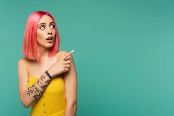 Verblüffte junge Frau mit rosa gefärbten Haaren, die mit dem Finger auf Türkis balanciert — Stockfoto