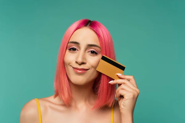 Glückliche junge Frau mit rosa gefärbten Haaren hält Kreditkarte isoliert auf blauem Grund — Stockfoto