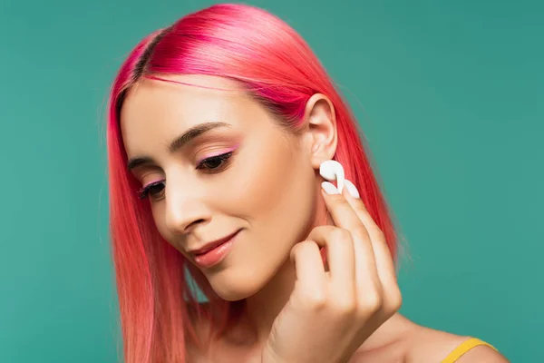 Jovem com cabelo tingido rosa segurando fone de ouvido sem fio isolado em azul — Fotografia de Stock