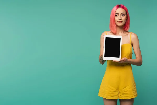 Erfreut junge Frau mit rosa gefärbten Haaren hält digitale Tablette mit leerem Bildschirm isoliert auf blau — Stockfoto