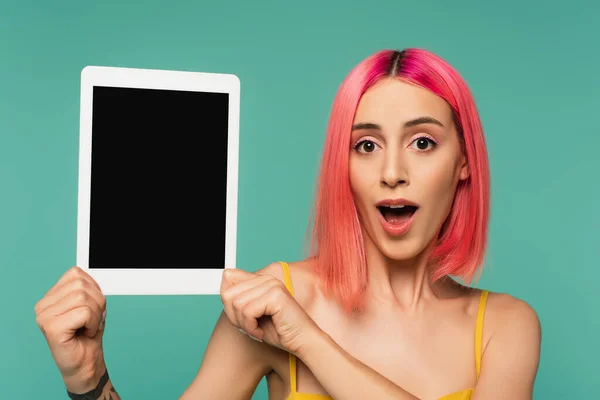 Stupito giovane donna con capelli rosa tinti in possesso di tablet digitale con schermo bianco isolato su blu — Foto stock