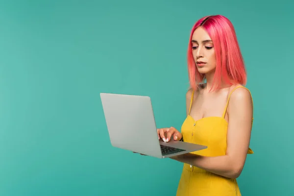 Jovem com cabelo tingido rosa usando laptop isolado em azul — Fotografia de Stock