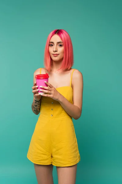 Junge Frau mit rosa gefärbten Haaren hält Pappbecher mit Kaffee to go isoliert auf blau — Stockfoto
