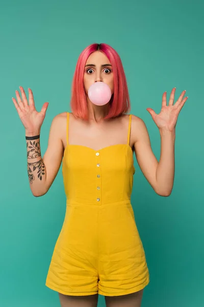 Schockierte junge Frau mit rosa gefärbten Haaren bläst Kaugummi isoliert auf blau — Stockfoto