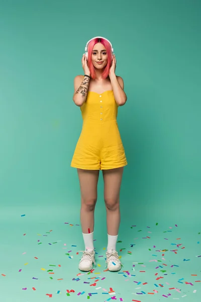 Full length of happy young woman with pink dyed hair in wireless headphones on blue — Stock Photo