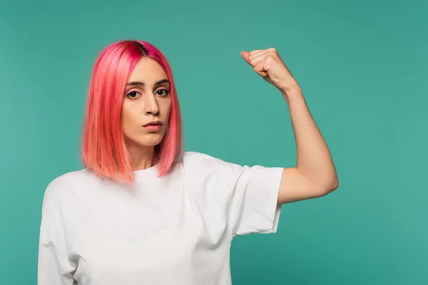 Сильная молодая женщина с розовыми окрашенными волосами, показывая мышцы изолированы на синий — стоковое фото