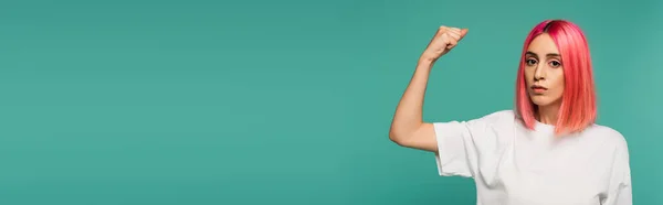 Forte giovane donna con capelli rosa tinti mostrando muscolo isolato su blu, banner — Foto stock
