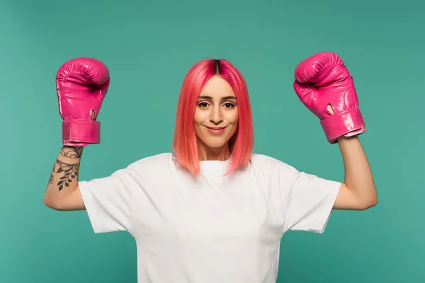 Joyeuse jeune femme aux cheveux teints en rose dans des gants de boxe isolés sur bleu — Photo de stock