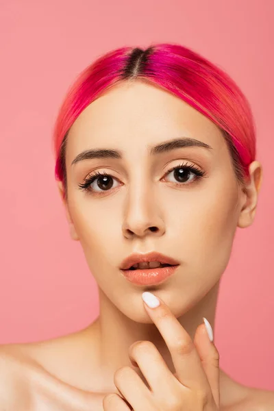 Bonita mujer joven con el pelo colorido y la piel perfecta mirando a la cámara aislada en rosa - foto de stock