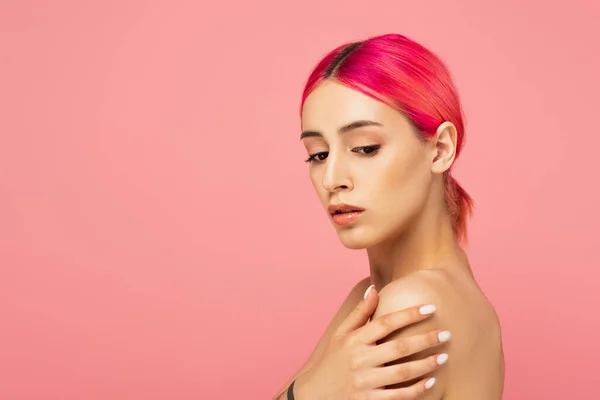 Hübsche junge Frau mit bunten Haaren, die die nackte Schulter berührt, isoliert auf rosa — Stockfoto