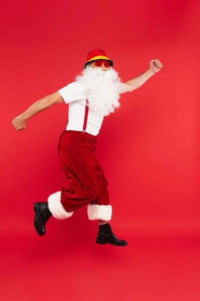 Santa claus in sunglasses levitating isolated on red — Stock Photo