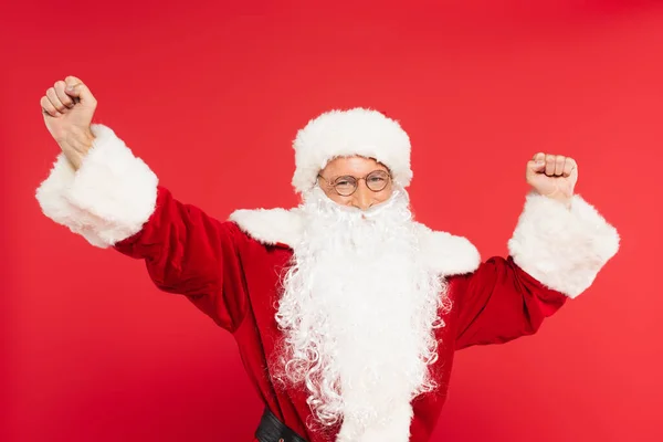 Père Noël dans les lunettes montrant un geste oui isolé sur rouge — Photo de stock