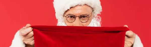 Santa claus covering face with sack isolated on red, banner — Stock Photo