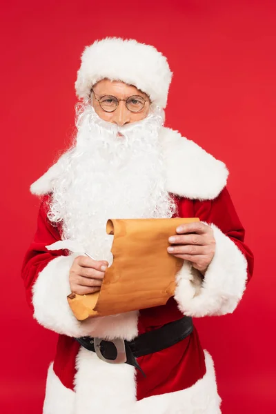 Papai Noel em traje escrevendo em papel isolado em vermelho — Fotografia de Stock