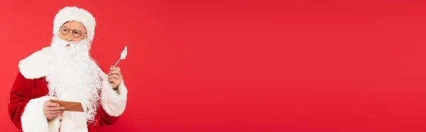 Pensive santa claus tenant enveloppe et stylo isolé sur rouge, bannière — Photo de stock