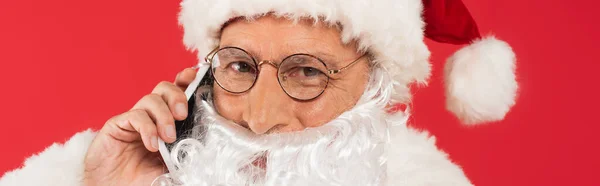 Santa in eyeglasses talking on smartphone isolated on red, banner — Stock Photo
