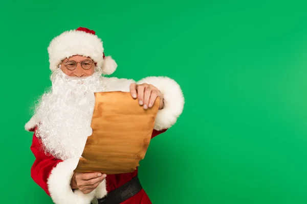 Père Noël dans les lunettes tenant le papier isolé sur vert — Photo de stock