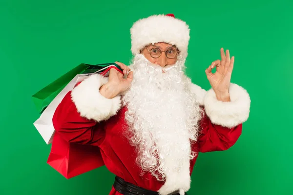 Санта-Клаус з сумками для покупок, що показують нормальний жест ізольовано на зеленому — стокове фото