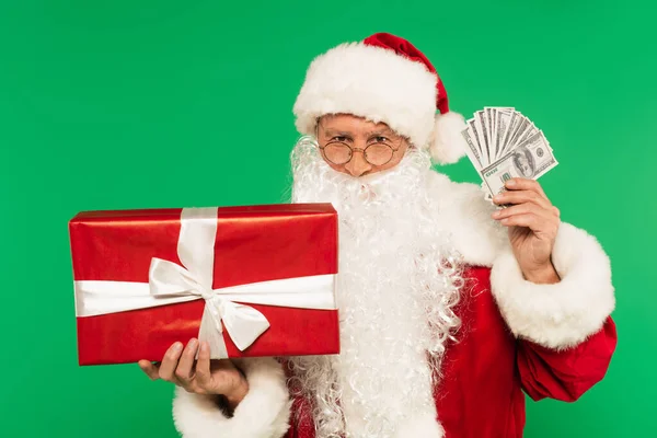 Santa claus holding gift box and cash isolated on green — Stock Photo