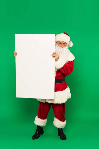 Papai Noel segurando cartaz com espaço de cópia no fundo verde — Fotografia de Stock