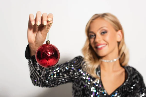 Closed up view of christmas ball in hand of blurred woman in shiny blouse on white — Stock Photo