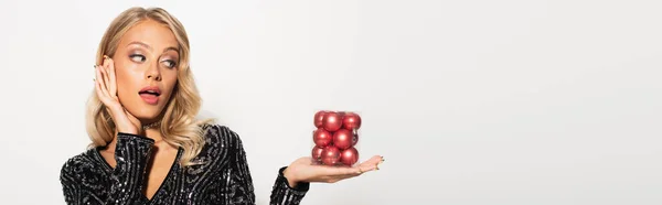 Mujer asombrada y elegante con conjunto de bolas de Navidad aislado en blanco, bandera - foto de stock