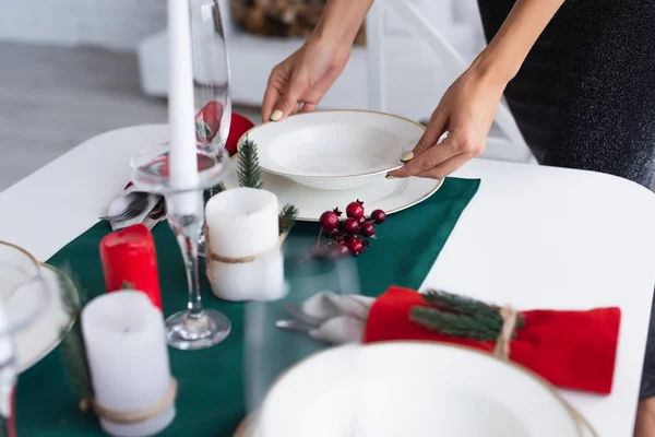 Cropped view of woman holding white plate while serving festive table — Stock Photo