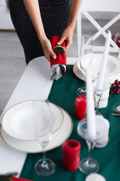 Vue partielle de la femme tenant des couverts enveloppés dans des serviettes de fête tout en servant la table — Photo de stock