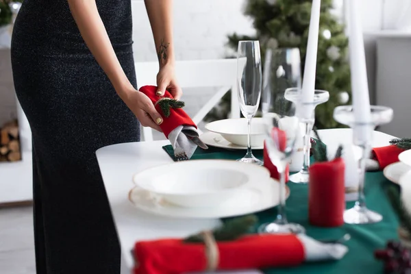 Partial view of woman setting table with cutlery wrapped in festive napkins — Stock Photo