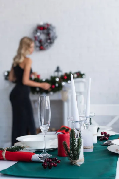 Table served for christmas celebration near woman decorating fireplace on blurred background — Stock Photo