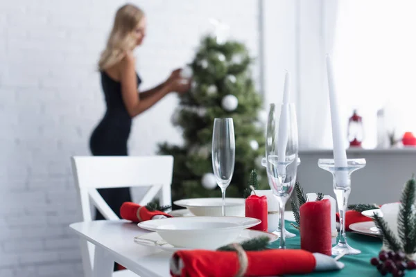 Selektiver Fokus des Serviertisches in der Nähe einer Frau, die den Weihnachtsbaum auf verschwommenem Hintergrund schmückt — Stockfoto