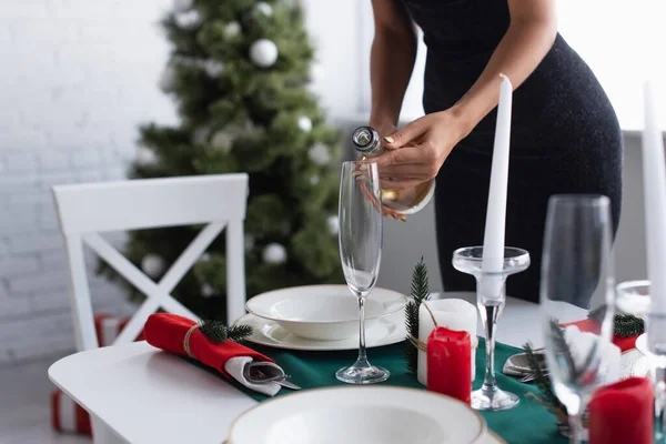 Vista ritagliata della donna versando champagne vicino albero di Natale su sfondo sfocato — Foto stock