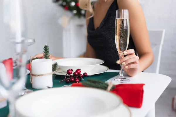 Visão parcial da mulher com copo de champanhe sentado na mesa festiva — Fotografia de Stock