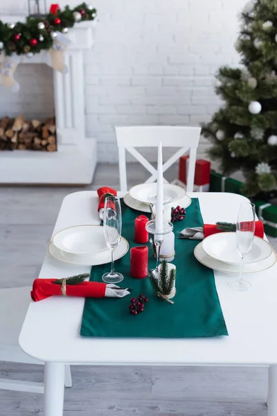 Vista ad alto angolo del tavolo servito per la cena festiva vicino all'albero di Natale su sfondo sfocato — Foto stock