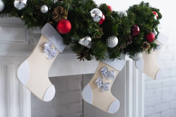 Fireplace with green pine garland decorated with baubles and christmas stockings — Stock Photo