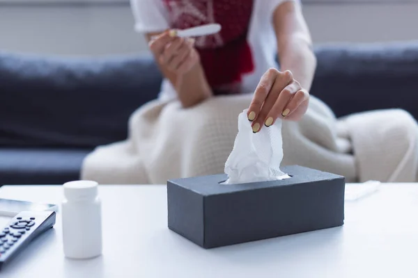 Ausgeschnittene Ansicht einer verschwommenen Frau mit Thermometer, die Papierserviette aus Packung nimmt — Stockfoto