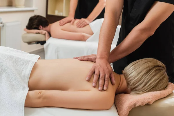 Masseur tut Massage auf den Schultern der jungen Frau in der Nähe Kollegen und Mann im Wellness-Center — Stockfoto