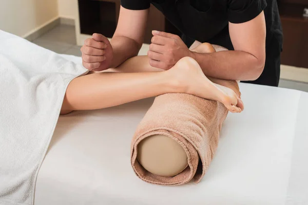 Cropped view of masseur doing massage on feet of woman in spa center — Stock Photo