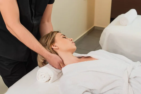 Masseur faisant massage du cou à la femme en peignoir — Photo de stock