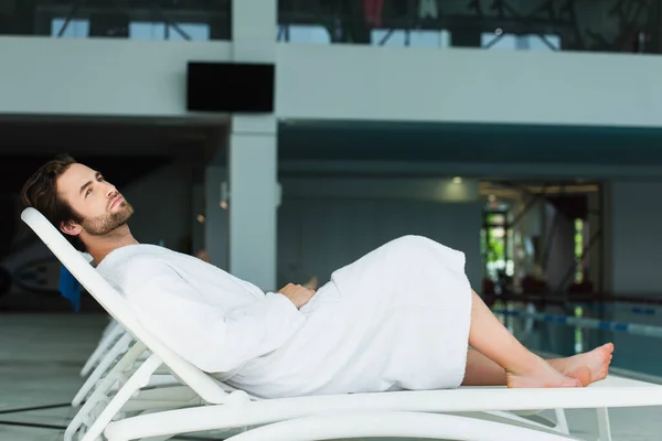 Young man relaxing on deck chair in spa center — Stock Photo