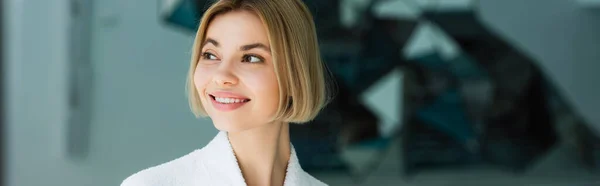 Mujer sonriente en albornoz mirando hacia otro lado en el centro de spa, pancarta — Stock Photo