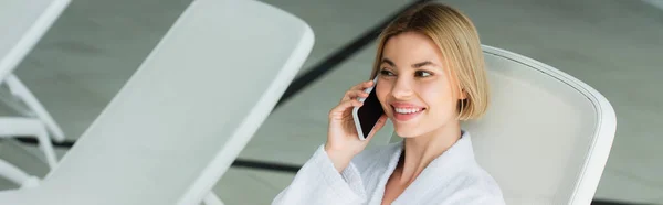 Mujer sonriente hablando por teléfono móvil en el centro de spa, pancarta - foto de stock