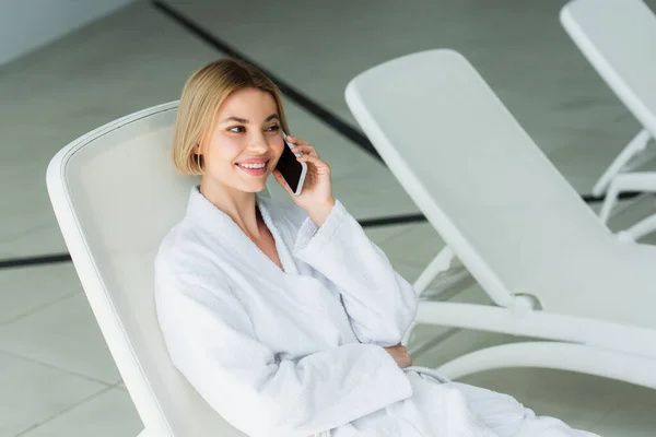 Mujer positiva hablando por teléfono móvil en el centro de spa - foto de stock