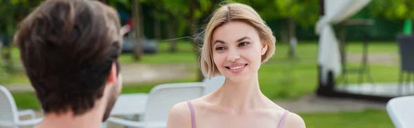 Mulher sorridente em maiô olhando para o namorado borrado no resort, banner — Fotografia de Stock