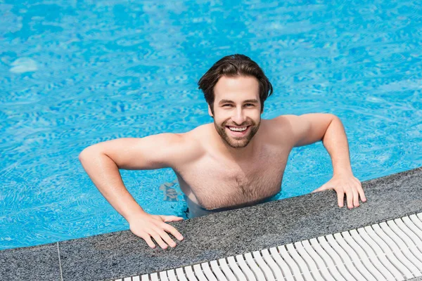 Hombre feliz mirando la cámara en la piscina durante el fin de semana - foto de stock