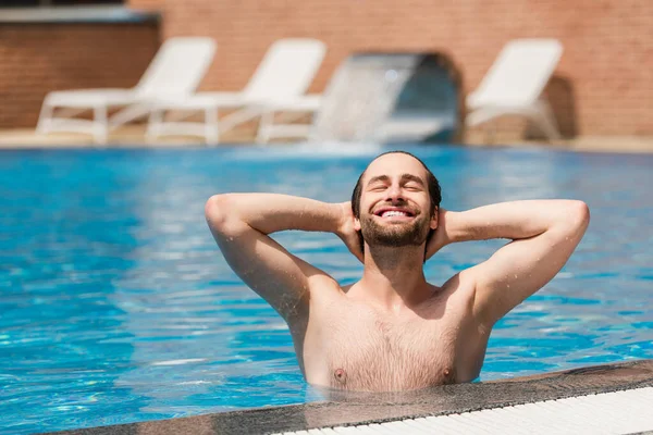 Радостный мужчина расслабляется в бассейне на открытом воздухе — стоковое фото