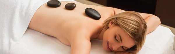 Giovane donna con pietre calde sul retro sul tavolo da massaggio nel centro benessere, banner — Foto stock